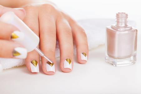 Close up of hands applying white nail polish