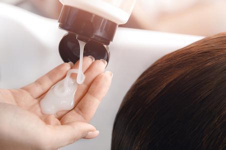 hand squeezing shampoo out of bottle