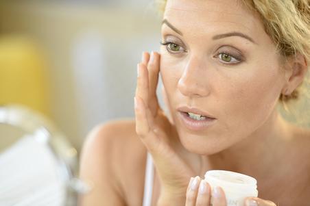 Middle-aged blonde woman applying face cream