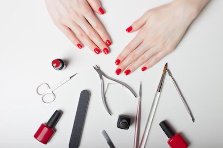 Photo of hands surrounding by nail tools to achieve a manicure
