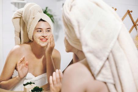 woman applying face scrub in the mirror