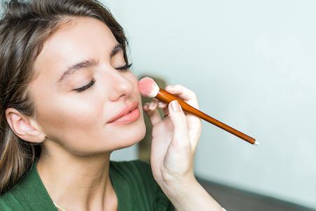 woman applying powder with makeup brush