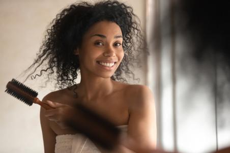 woman brushing curly hair post-shower