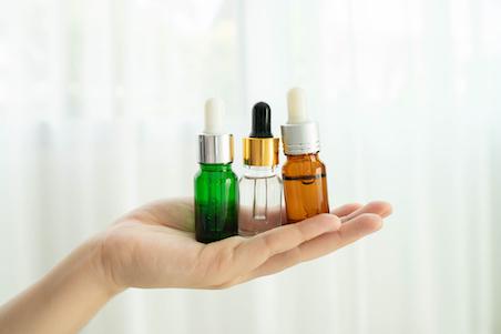 Woman hand holding dropper glass bottles over white background