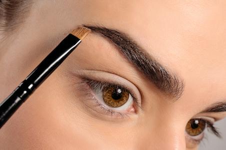 woman holding a makeup brush close to her eyebrow