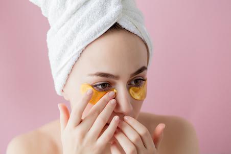 woman in towel applying under eye masks