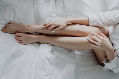 Woman in white sheets holding legs