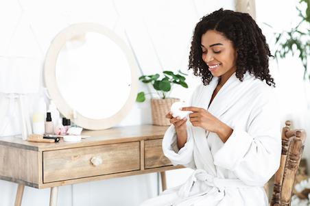 woman smiling holding tub of hair cream