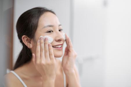 woman washing her face with cream cleanser