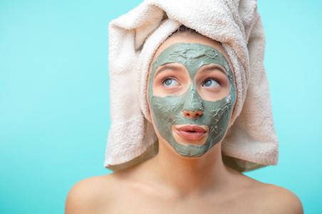 woman with green face mask and towel on her head