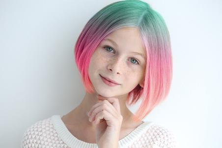 Young girl with colourful dyed hair on white background