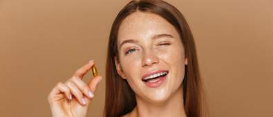 Winking and smiling woman holding a supplement