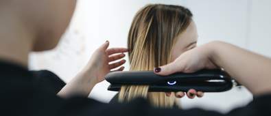 a person straightening a woman's hair