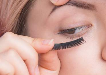 woman holding an eyelash up to her eye