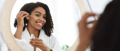 Woman applying serum in the mirror