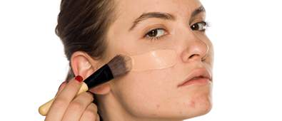 woman with problematic skin applying foundation
