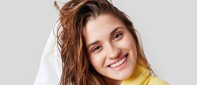 Young girl towel drying her hair while smiling at the camera