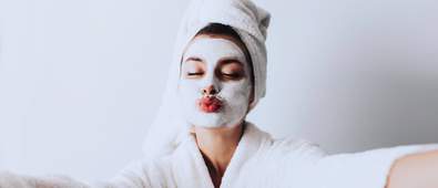 woman taking a selfie with face mask on and dressing gown and towel