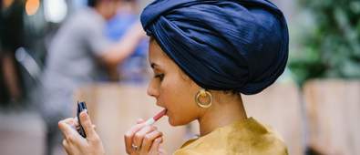 muslim woman applies lipstick