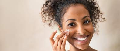 smiling women applying cream to her cheek