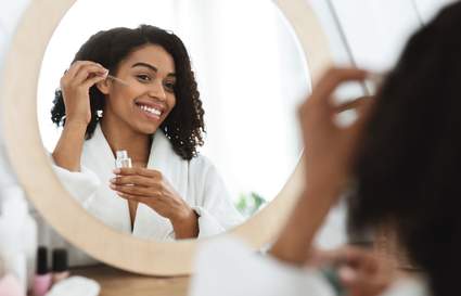Woman applying serum in the mirror