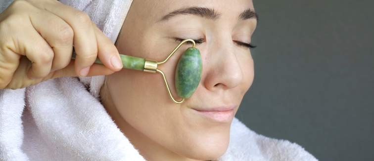 Women in a towel using a face massage roller