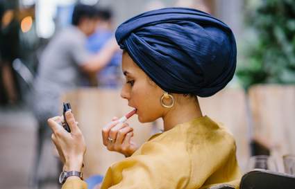 muslim woman applies lipstick