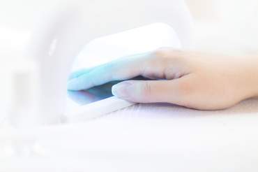 woman drying gel nails under a UV lamp