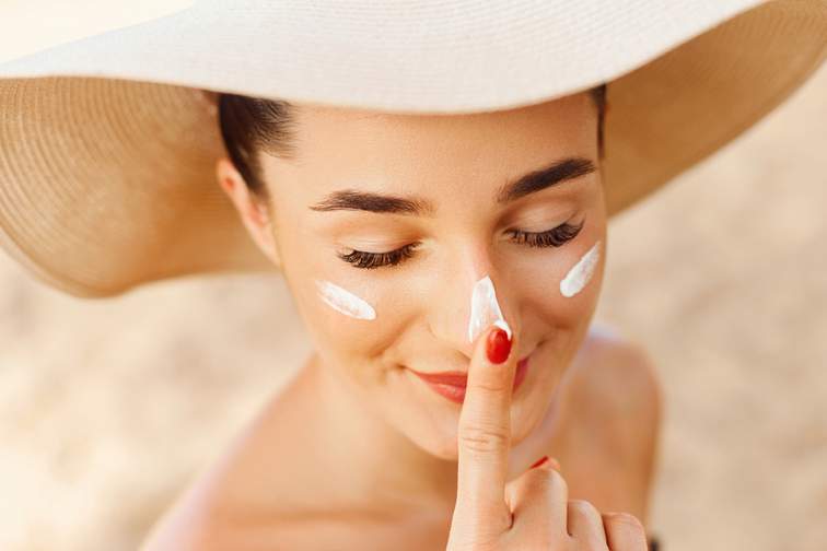 Woman dotting sun tan lotion onto face
