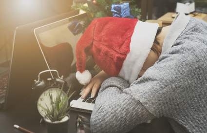 Woman sleeping on desk in a Santa hat