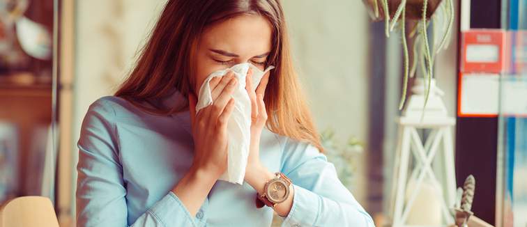 ill woman blowing her nose at table